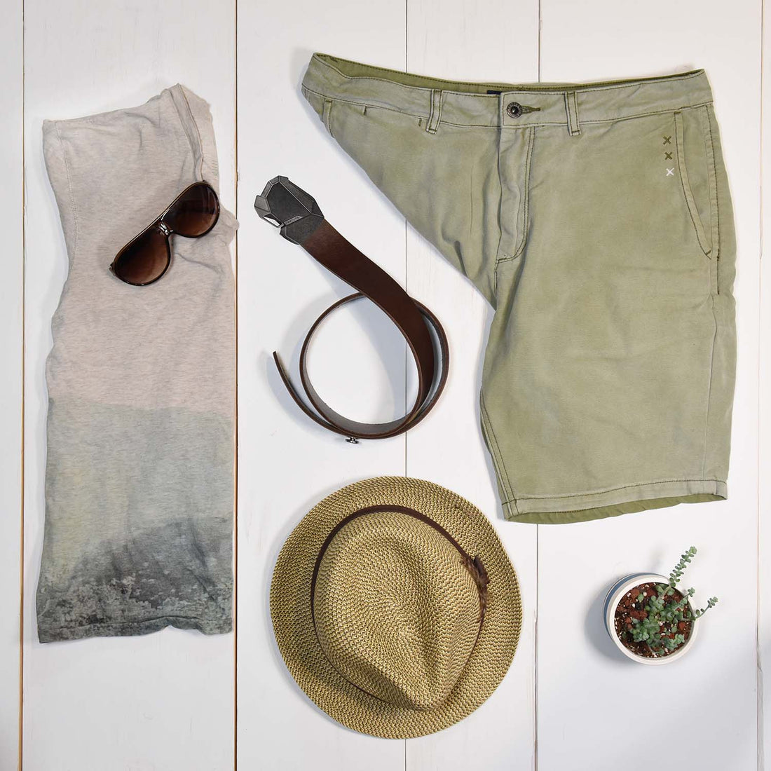 mens brown belt styled with green khaki shorts, summery shirt, and straw hat.