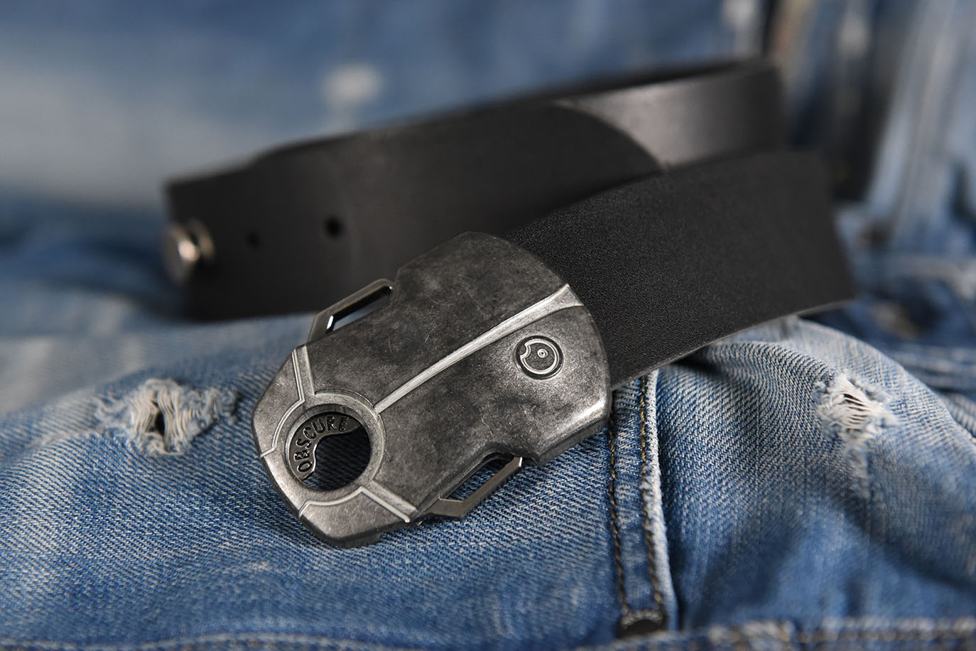 Black belt with silver buckle shaped like a scarabe beetle on a blue denim background