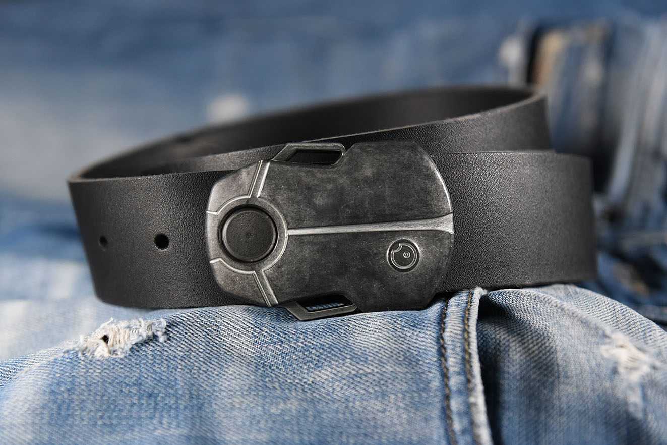 Black leather belt with a metallic buckle shaped like scarab beetle on blue jeans