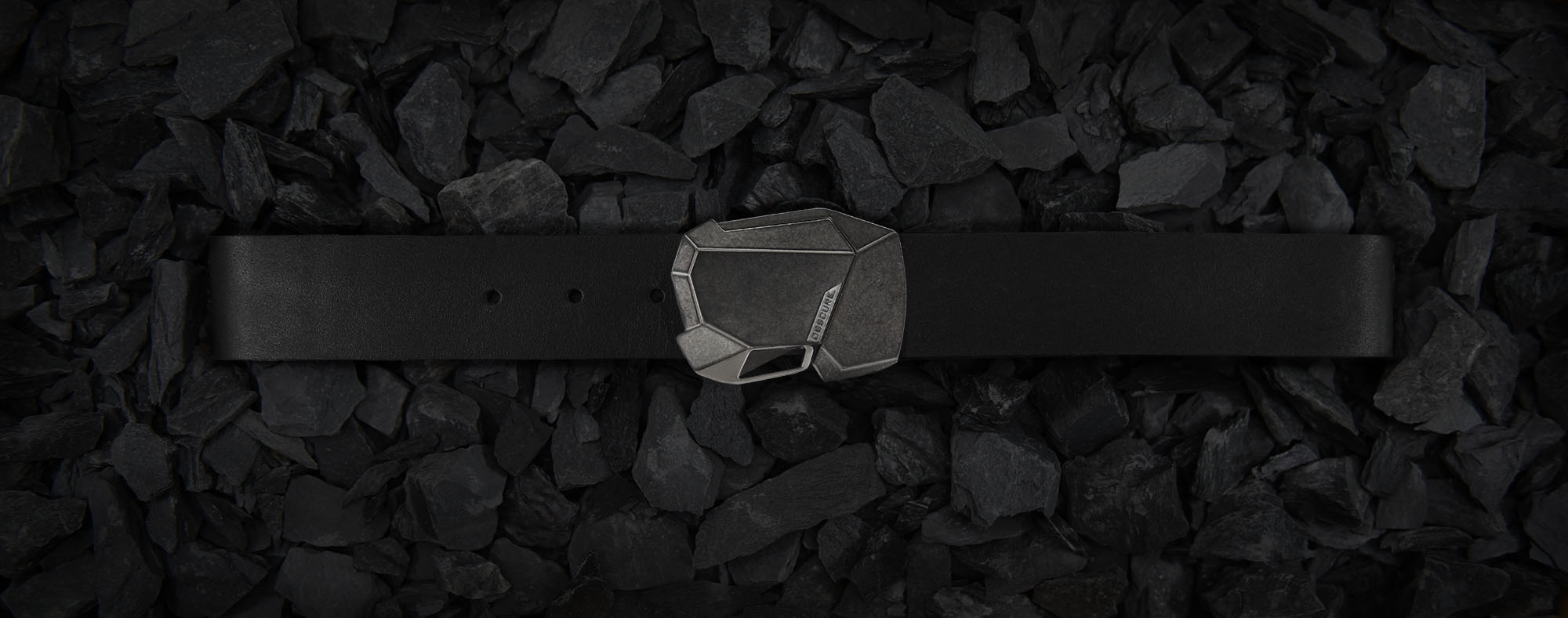 edgy cyberpunk belt buckle on handmade black leather belt on a bed of slate stones