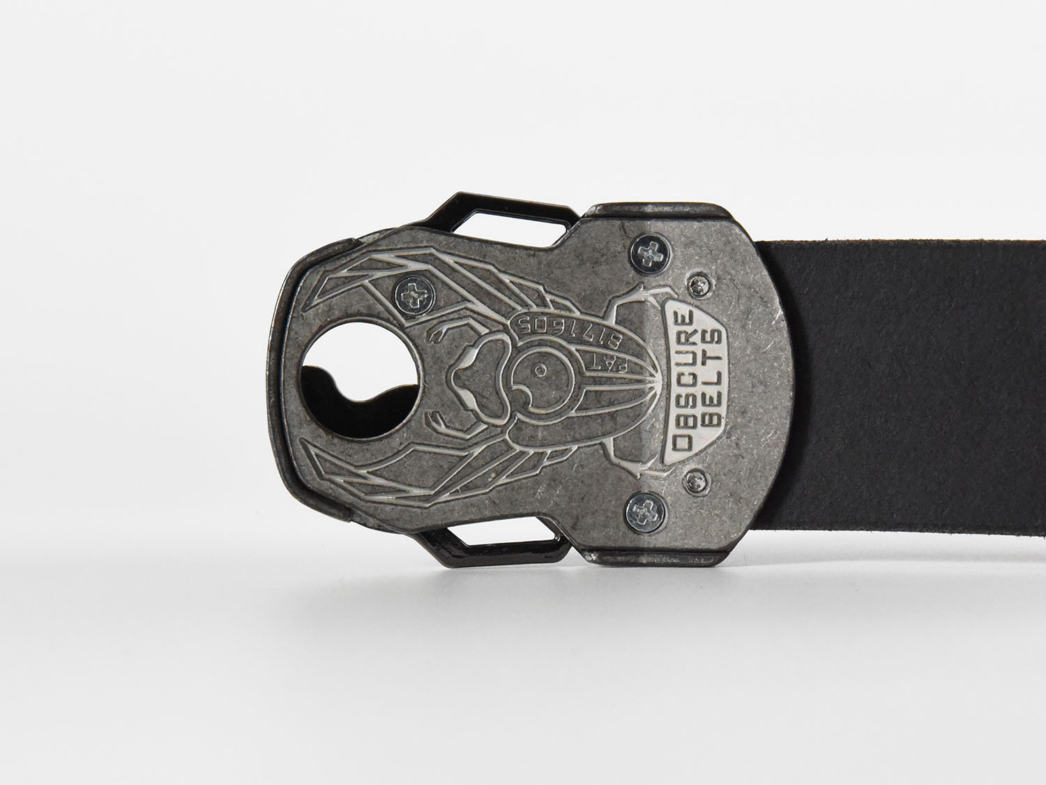 The back of the unique silver belt buckle has a recessed scarab beetle design etched in white with the words "Obscure Belts" and the patent number.