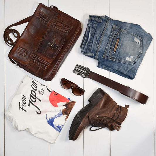 men's style flat lay with blue jeans, t shirt, and brown leather western men's accessories.