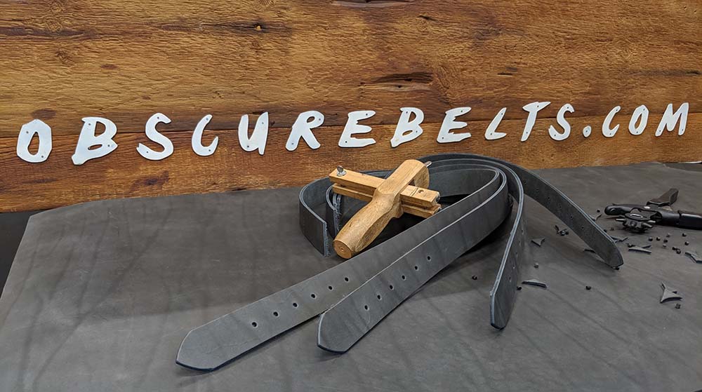 obscure belts makes the best custom belts. wooden sign with leather hand tools and straps ready to tailor to fit your waist.