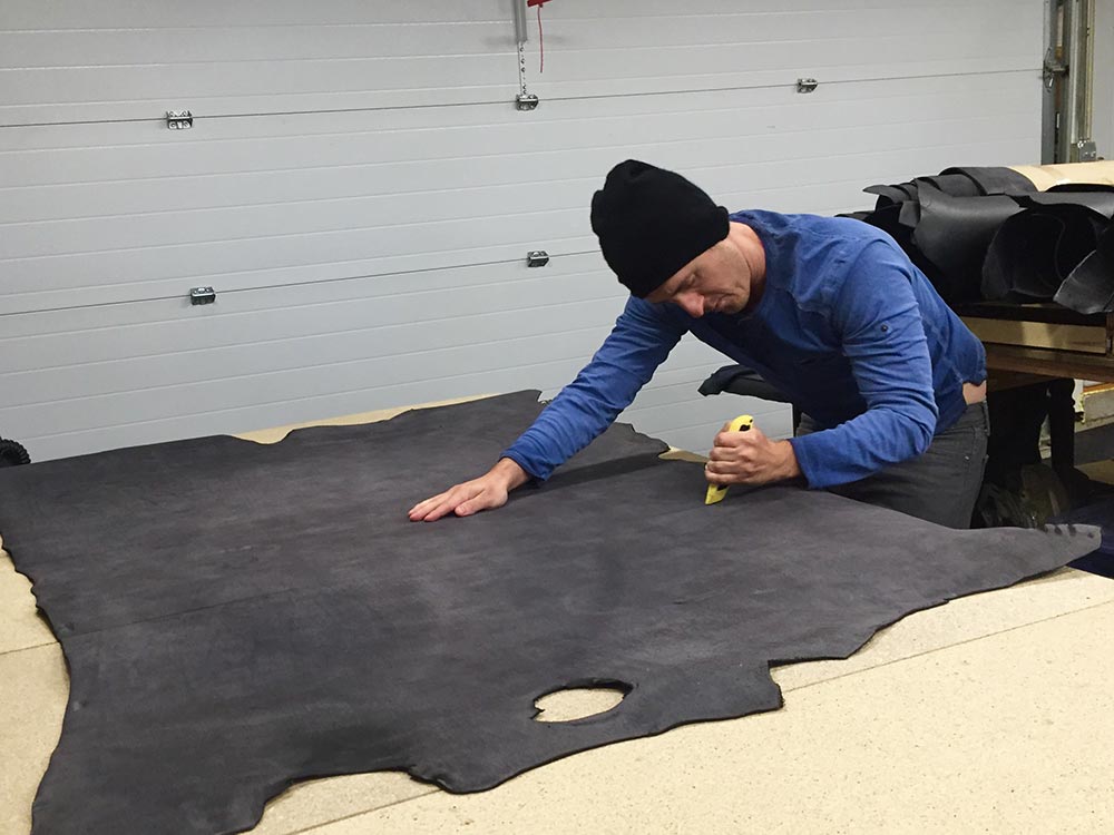 artisan squaring off a leather hide to get it ready to make into handmade belts