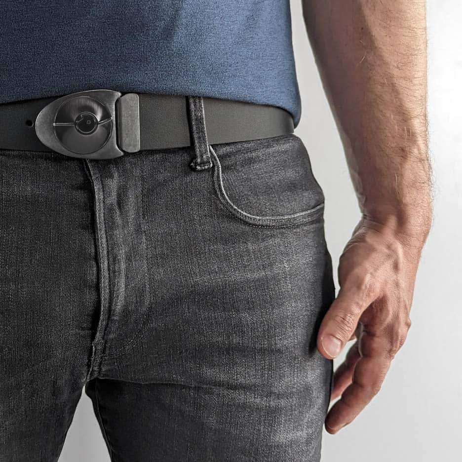 Person wearing cool arrowhead shaped belt buckle on a black leather belt with a navy blue shirt and faded black jeans.