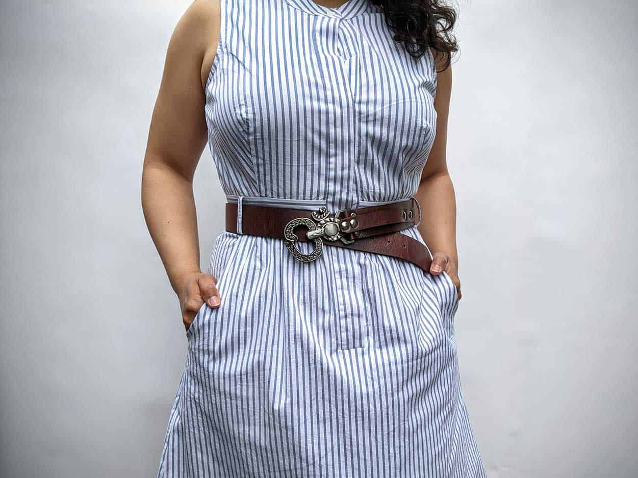 woman wearing pinstripe dress with waist cinching brown leather belt with elaborate ohm belt buckle